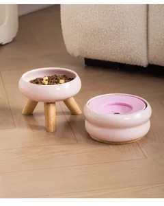 Detail van roze keramische voerbakken met houten standaard en spatvrije drijvende schijf