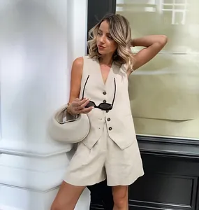 Stylish woman wearing a khaki linen vest and shorts set in a bright urban outdoor setting.