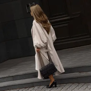 Side view of an oversized beige trench coat with lantern sleeves and a side slit design