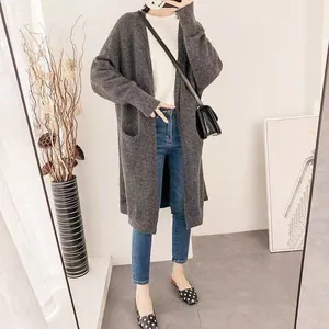 Detail view of a long dark grey knitted cardigan styled with jeans and a bag.