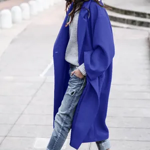 Stylish royal blue oversized wool coat for women over a grey sweater on an outdoor walkway.