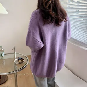 Back view of a loose purple knitted cardigan sweater in a cozy minimalist room