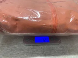Detail view of an orange terracotta puffer jacket being weighed on a silver digital scale