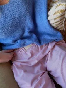 Nahaufnahme einer gestreiften Hose in Rosa und eines blauen flauschigen Pullovers.