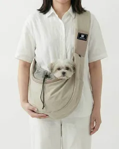 Detailed view of a beige crossbody pet carrier bag with a small dog looking out mesh