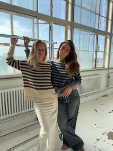 Dos modelos luciendo cómodos jerséis de rayas oversize en una habitación luminosa