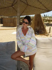 Fashionable woman wearing a multicolor striped hooded knit cardigan at a beach resort