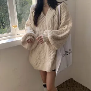 Dettaglio di un pesante maglione a trecce color crema con scollo a V per un look invernale.