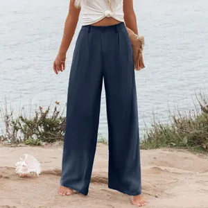 Dettaglio dei pantaloni blu navy a vita alta e gamba larga indossati da una modella in spiaggia