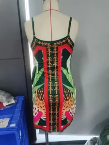 Detail view of tropical floral print on a green spaghetti strap dress on mannequin.