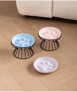 Detail of ceramic slow feeder pet bowls with cat paw design and black wire stands