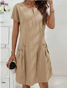 Close-up view of a beige cotton linen dress with zipper neckline and decorative side pockets