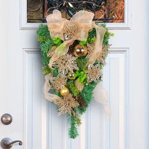 Elegant golden Christmas pine needle teardrop swag wreath hanging on a front door