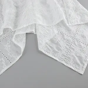Détail du tissu en coton blanc avec broderie anglaise complexe et motifs floraux