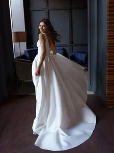 Elegant floor-length white evening gown featuring a deep V back and long flowing train