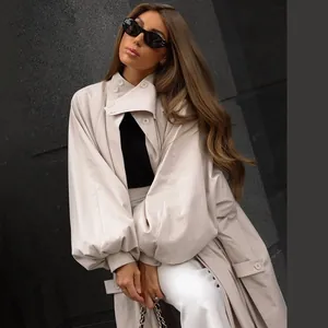 Detailed view of women's beige trench coat with chic lantern sleeves and stand collar.