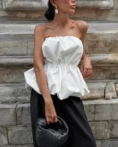 Close-up of elegant white strapless ruffled top with cinched waist shown on model