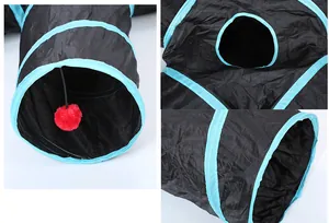 Detail view of black collapsible cat tunnel with blue trim and red hanging ball.