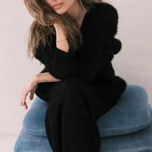 Close-up detail of a soft black mink velvet V-neck knitted sweater on a seated model