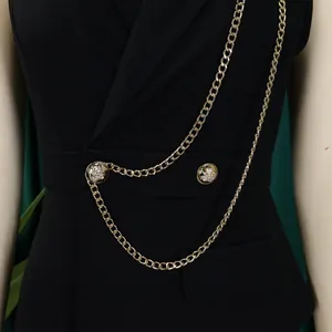 Close-up of golden chain and embossed button details on black suit collar jumpsuit