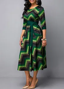 Detail of a plus-size crew neck dress featuring green chevron print and a tie waist