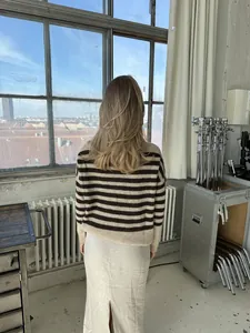 Vista trasera de una mujer con un suéter de punto de rayas marrones y beige de corte relajado