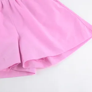 Gros plan détaillé de l'ourlet du short en coton rose montrant la texture du tissu.