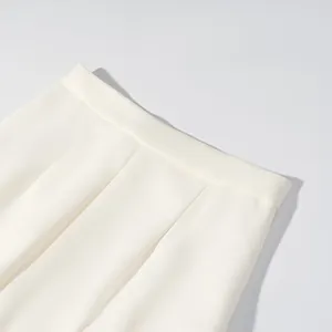 Detailed close-up view of off-white lantern trousers waist showing elegant pleats and fabric.