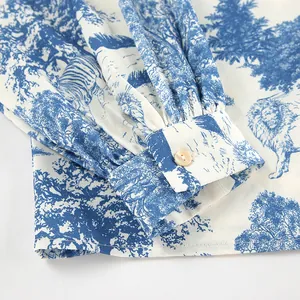 Detail of blue and white toile de jouy print blouse with lantern sleeve and button.