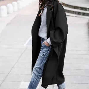 Detailed side view of a black woolen long coat styled with ripped jeans and street background.