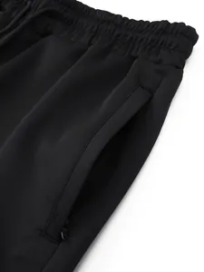 Close-up of black sports sweatpants with elastic waistband and zipper pocket detail