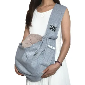 Woman wearing a grey pet sling carrier featuring a side pocket for a smartphone