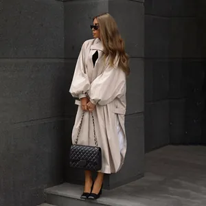 Detail view of stylish beige oversized trench coat with lantern sleeves and side slits.