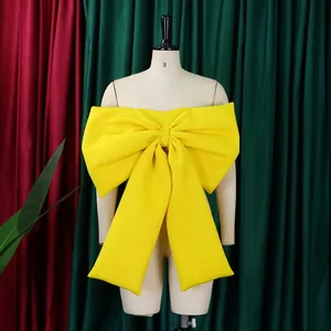 Dettaglio di un top a fascia con fiocco oversize giallo brillante su un manichino.