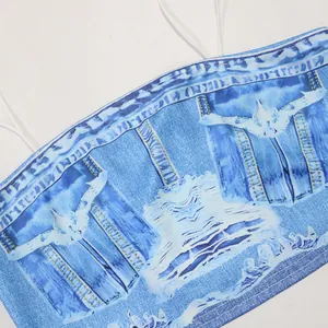 Détail macro montrant l'imprimé denim bleu et le motif d'aile sur un haut à bretelles