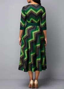 Back view of a round neck midi dress with green zigzag print and belted waist