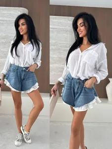 Dettaglio degli shorts in denim lavato a vita alta con orli a balze bianche a strati