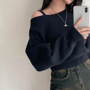 Dettaglio di un maglione in maglia blu scuro con spalle scoperte e polsini a coste.
