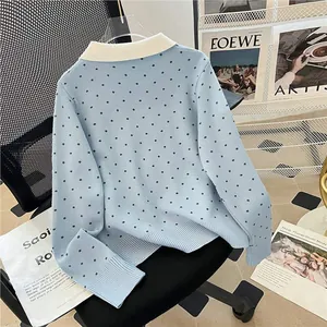 Light blue polka dot knit cardigan with white collar displayed on a black office chair
