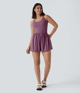 Full body view of a woman wearing a purple sleeveless knit romper with gathered waist.