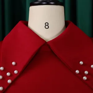 Detailed close-up view of red dress Peter Pan collar featuring elegant pearl bead decorations