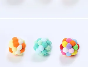 Detailed view of three handmade colorful pom-pom cat balls for interactive play.