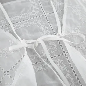 Vue détaillée de la broderie anglaise blanche et des liens délicats sur le tissu