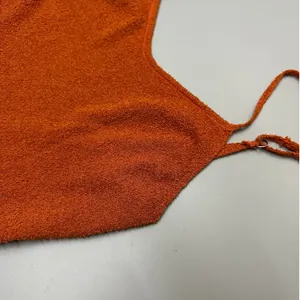 Close-up of the textured orange knit fabric and strap detail of the backless dress