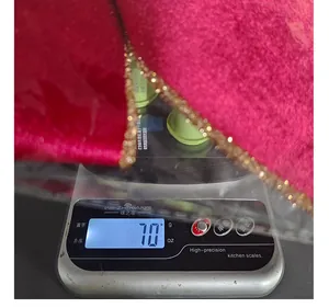 Detailed view showing the weight of a red velvet Christmas bow with gold glitter trim.