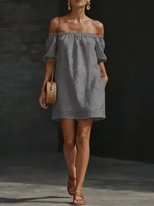 Full body view of a grey off-the-shoulder cotton linen loose mini dress with straw bag
