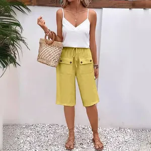 Detailed view of women's yellow loose drawstring shorts featuring functional buttoned pockets