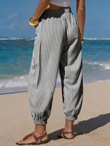 Back view of women's striped faux linen cuffed pants on a sunny beach vacation