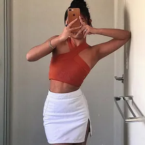Detail of a sexy orange cross halter neck knit crop top with ribbed texture on a model