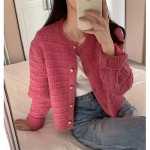 Spiegelselfie van een vrouw met een roze retro gebreid vest met gouden knopen.